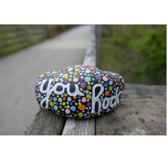 Photograph of a rock painted with colorful dots and the phrase "you rock"