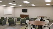 Chairs and tables facing a white board and TV in the new program area.